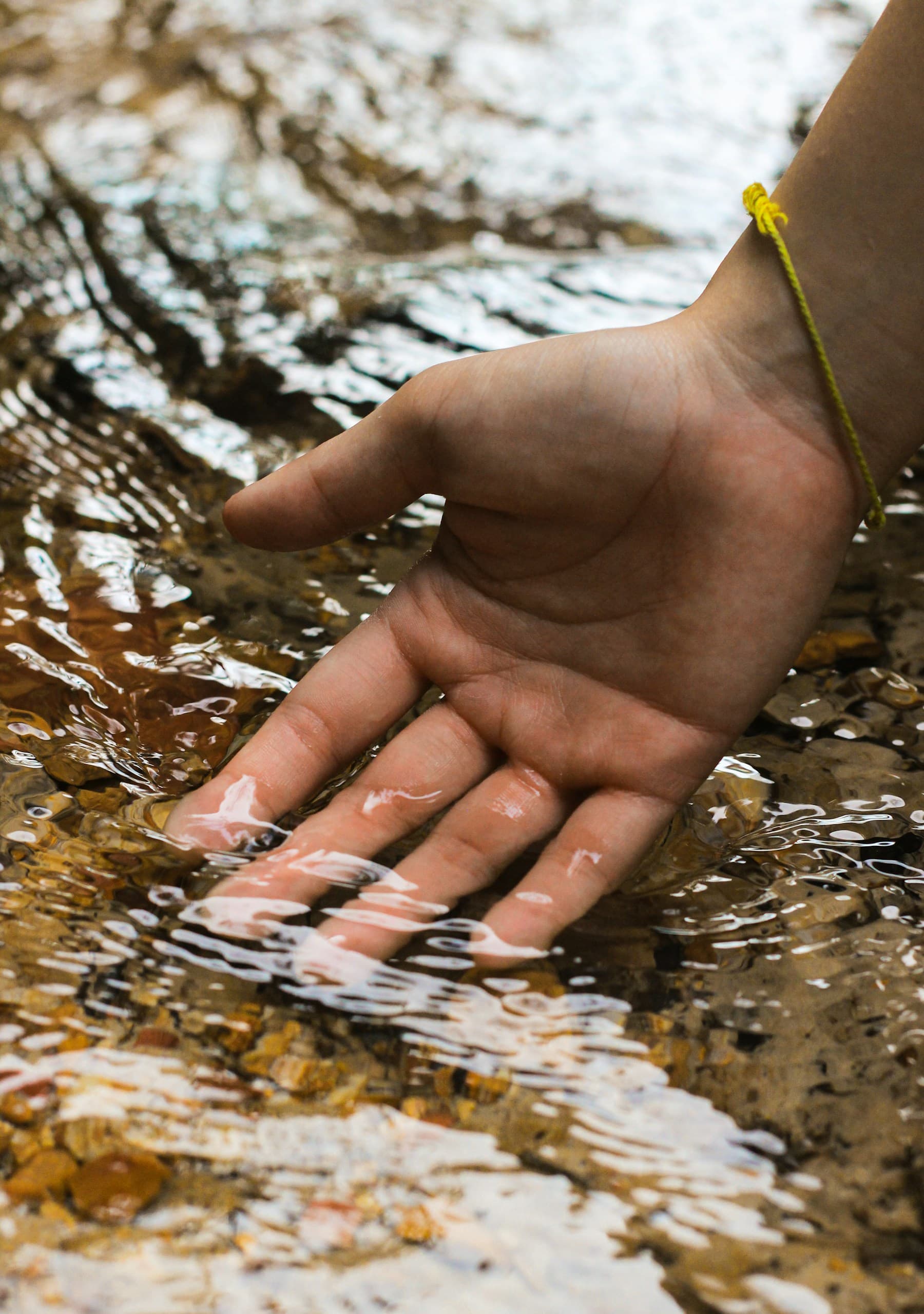 A hand resting in clear, sunlit water